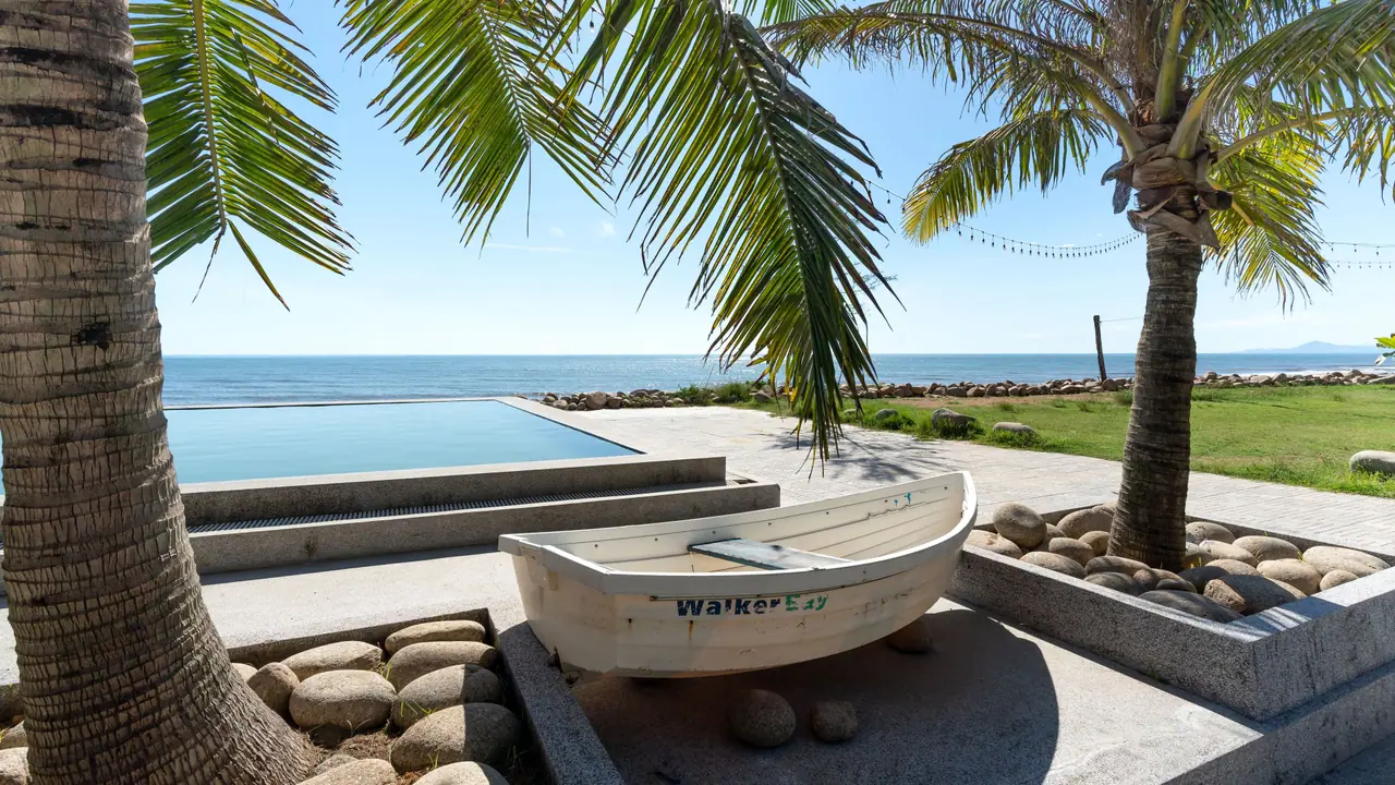 Outdoor pool under coconut palms beside a calm sea