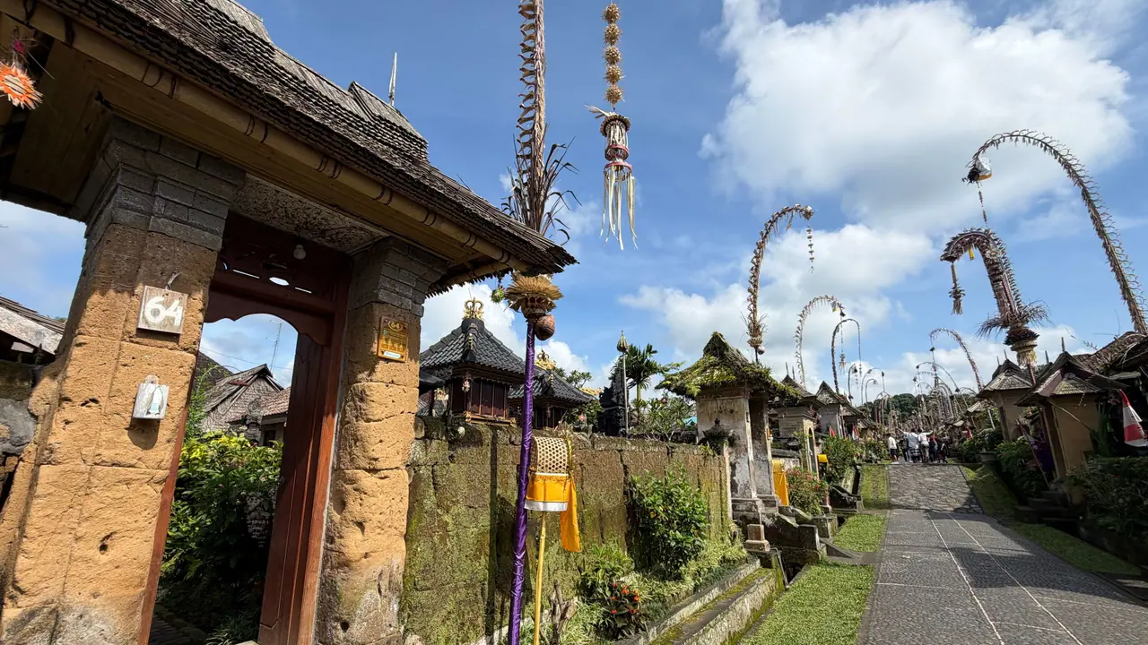 Lane in a traditional Balinese village with stone gates and penjor poles